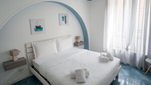 A neatly made bed with white linens, a bedside table with a lamp, and a window with sheer curtains. - Casa Belmonte (Como)