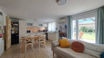 A compact living space with a kitchenette, dining area, and a sofa with cushions.