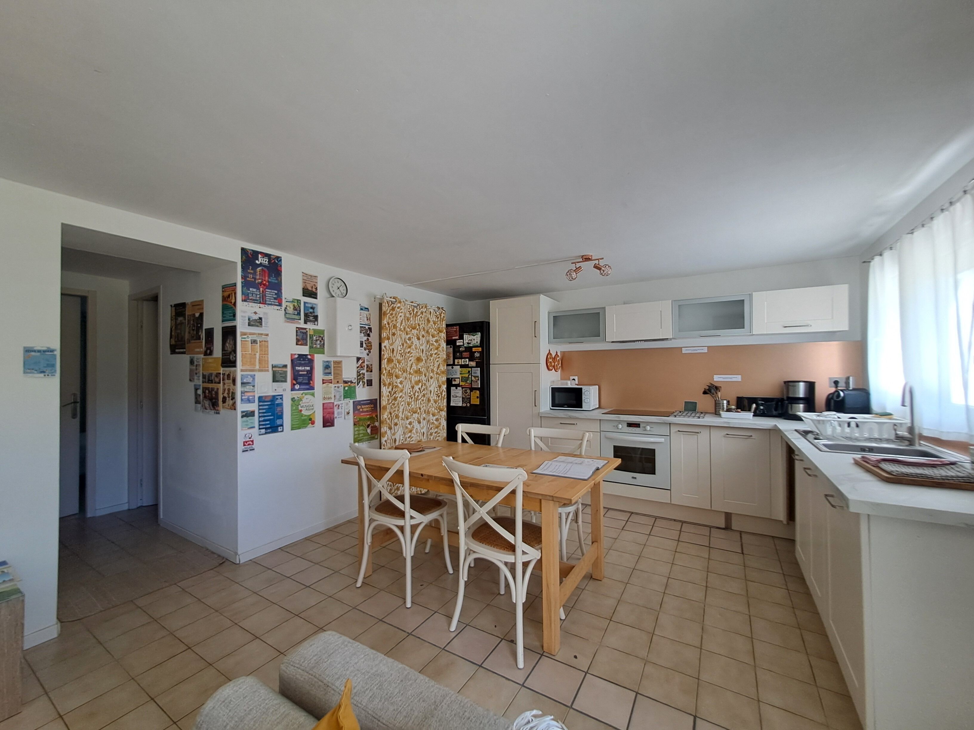 A compact kitchen with a dining area, a refrigerator, microwave, and a sink.