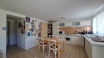 A compact kitchen with a dining area, a refrigerator, microwave, and a sink.