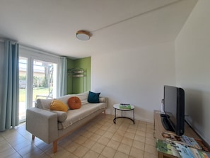 Un salon avec un canapé, une petite table, un téléviseur et un mur vert.