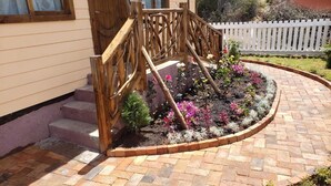 Un jardín con una escalera de madera que conduce a una casa.