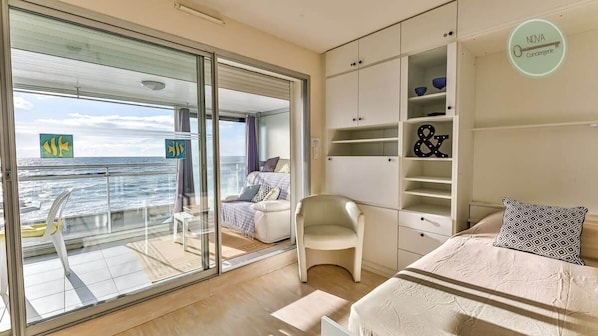 A modern bedroom with a balcony, a bed, a chair, and a wardrobe.