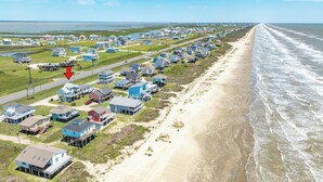 An aerial view of a coastal residential area with houses along the beach, a road, and a body of water. - Sun, Sand & Surf Await! 3rd House from Beach, Dogs Welcome, Fenced Area, 2 Decks (Galveston)