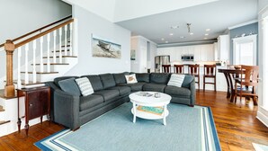 A modern living room with a sectional sofa, a round coffee table, and hardwood flooring. - Sun, Sand & Surf Await! 3rd House from Beach, Dogs Welcome, Fenced Area, 2 Decks (Galveston)