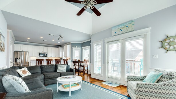 A spacious living room with a gray sectional sofa, a patterned armchair, and a coffee table. - Sun, Sand & Surf Await! 3rd House from Beach, Dogs Welcome, Fenced Area, 2 Decks (Galveston)