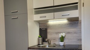 Una cocina moderna con gabinetes grises, un lavamanos de acero inoxidable y un salpicadero de madera.