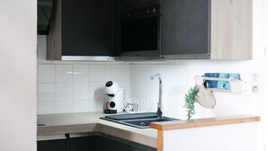 A modern kitchen with a built-in oven, a coffee maker, and a hanging pot rack. - Pretty flat with ocean and lake views Les Sables - sleeps 4 (Les Sables-d´Olonne)