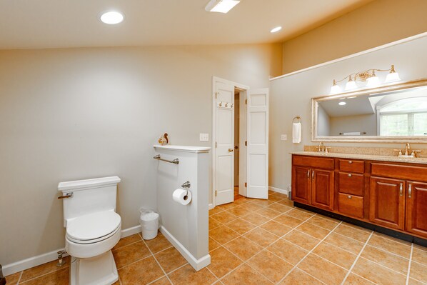 A bathroom with a toilet, a shower, and a vanity with a mirror. - Rustic Elegance w/ Hot Tub, Game Loft & Fireplace (Oakland)