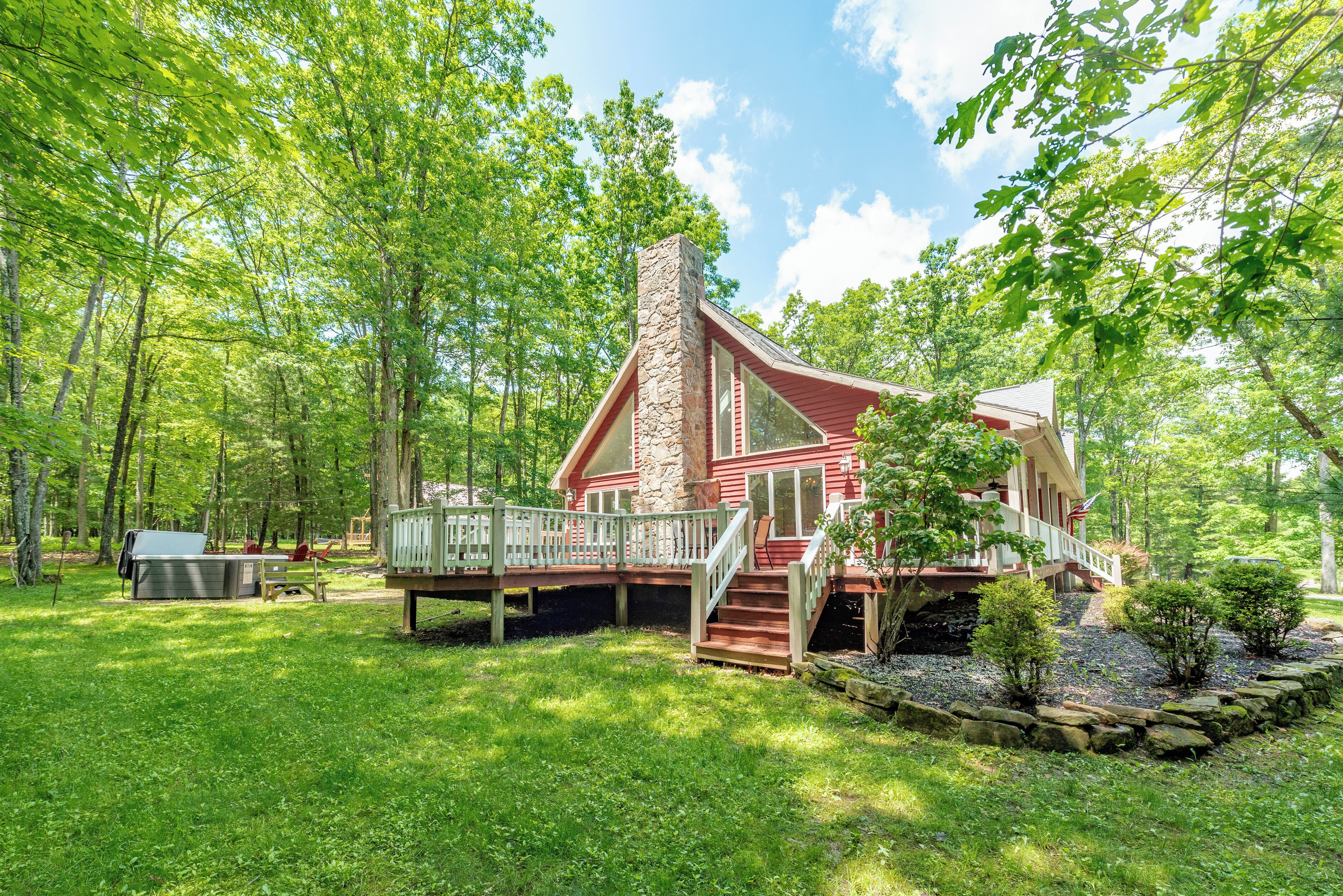 Eine Holzhütte mit Steinkamin, einer Holzterrasse und einer kleinen Veranda.