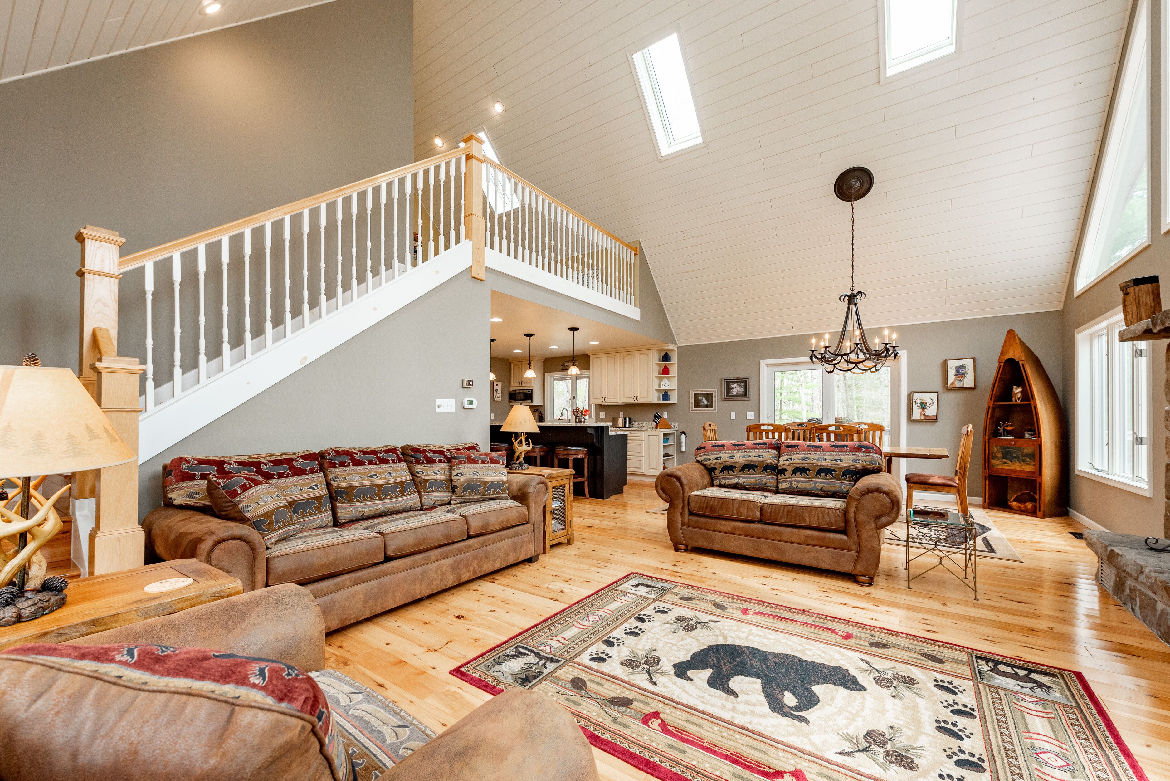 A spacious living area with a high ceiling, wooden flooring, and a staircase leading to an upper level.
