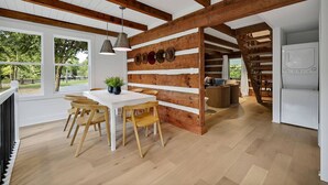 A modern kitchen with wooden beams, a white table, and a dining area with wooden chairs. - Luxury Modern Cabin* 5 Acres* Pickle Ball*Hot Tub (Primm Springs)