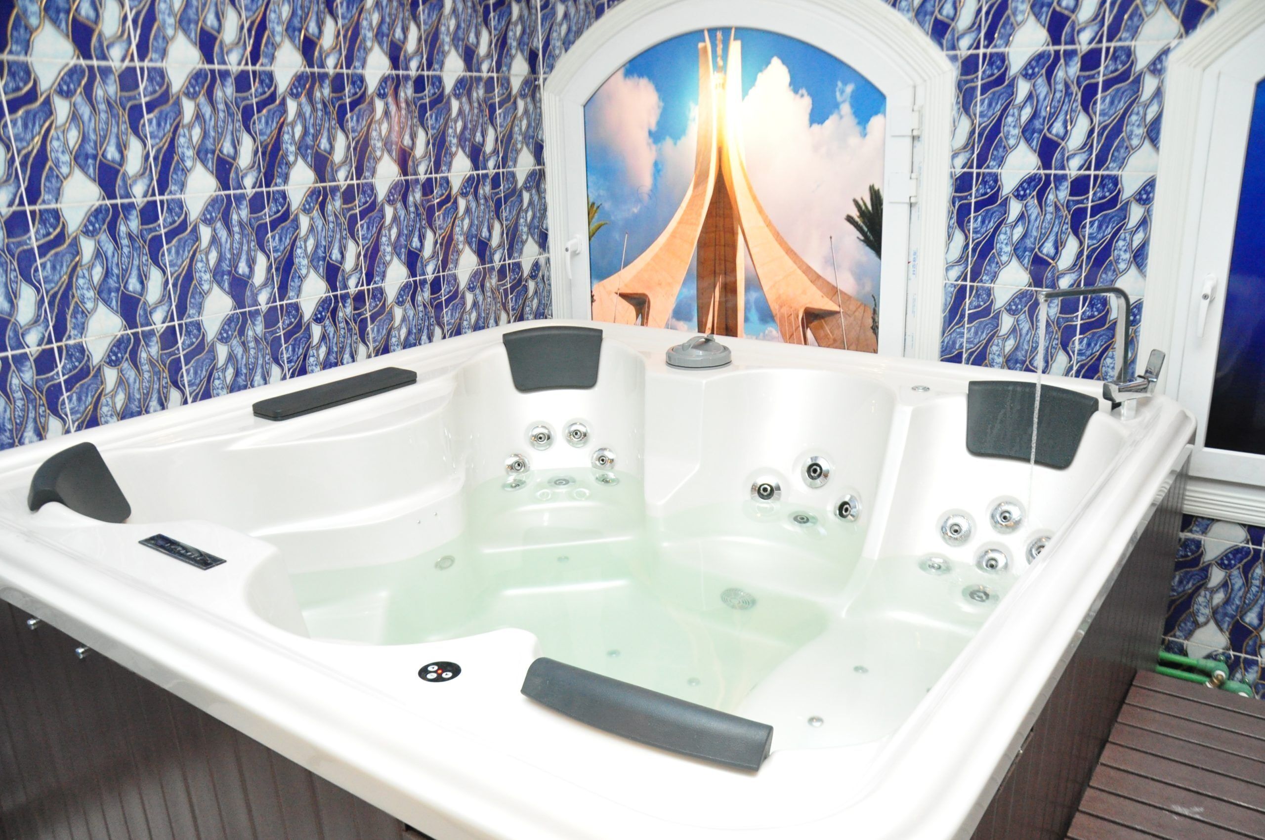 A spa area with a large bathtub, a shower, and a view of a bridge through a window.