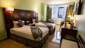 Een hotelkamer met twee bedden, een bureau, een stoel en een raam met gordijnen.