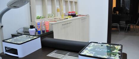 A reception desk with a desk lamp, a computer, and a shelf with various items.