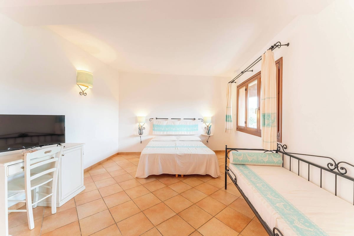 Een slaapkamer met een bed, bureau en televisie.