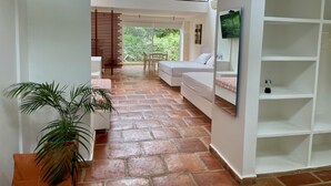 A modern hotel room with a large window, a flat-screen TV, a sofa, and a dining area with a table and chairs. - LA MASIA HOTEL BOUTIQUE (Anapoima)