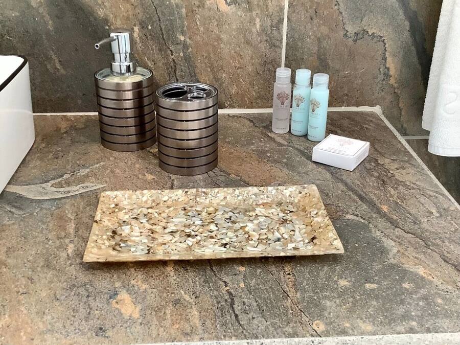 Una encimera de baño con un dispensador de jabón, dos recipientes cilíndricos y tres botellas de jabón líquido.
