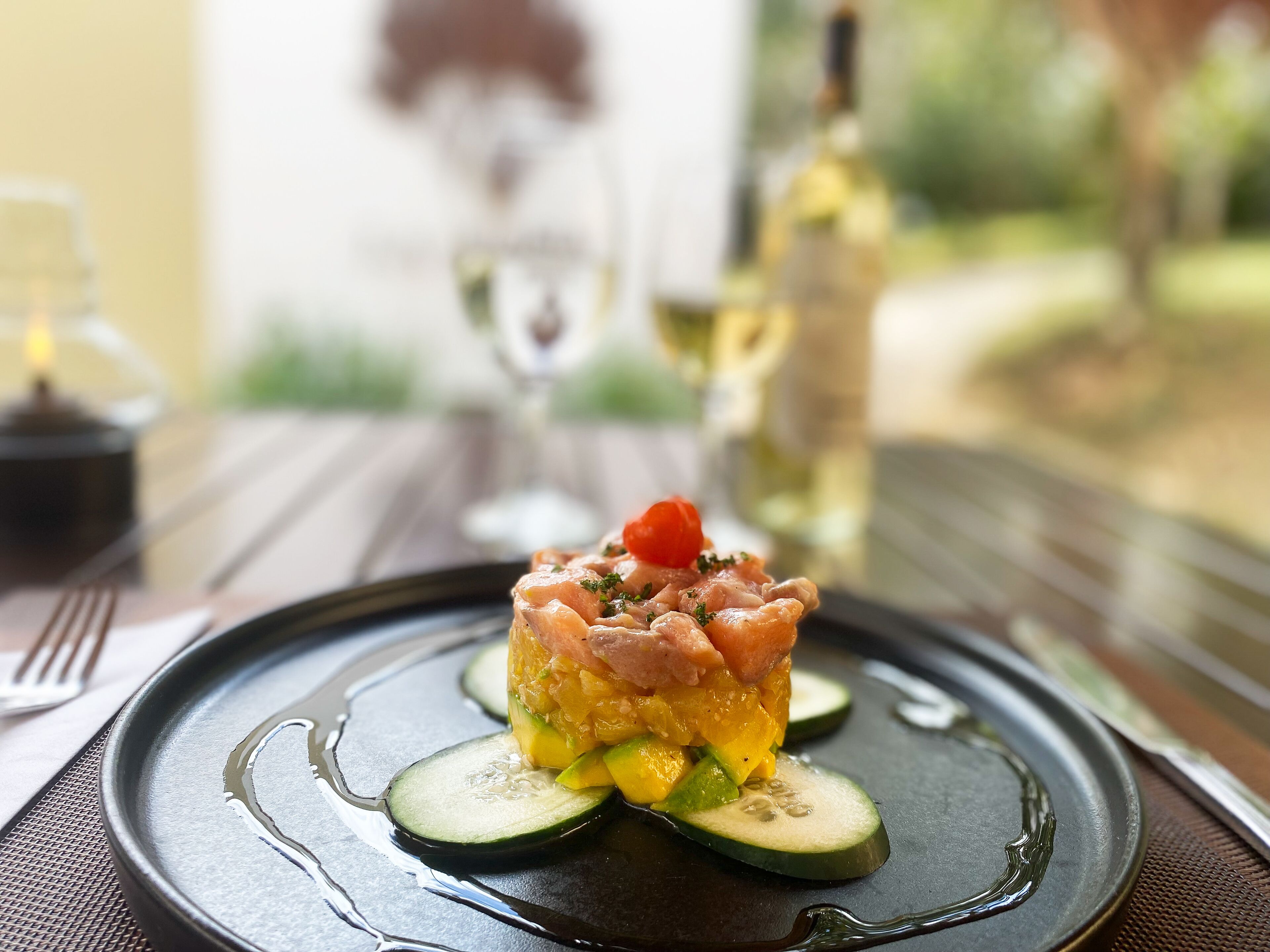 A plated dish with a garnish on a dark plate, set on a table with a placemat.
