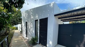 A modern house with a white exterior, a black garage door, and a covered patio area. - LA MASIA HOTEL BOUTIQUE (Anapoima)