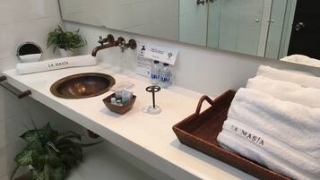A bathroom with a wooden sink, a towel rack labeled "LA MASIA", a small wooden basket, and a bottle of water.