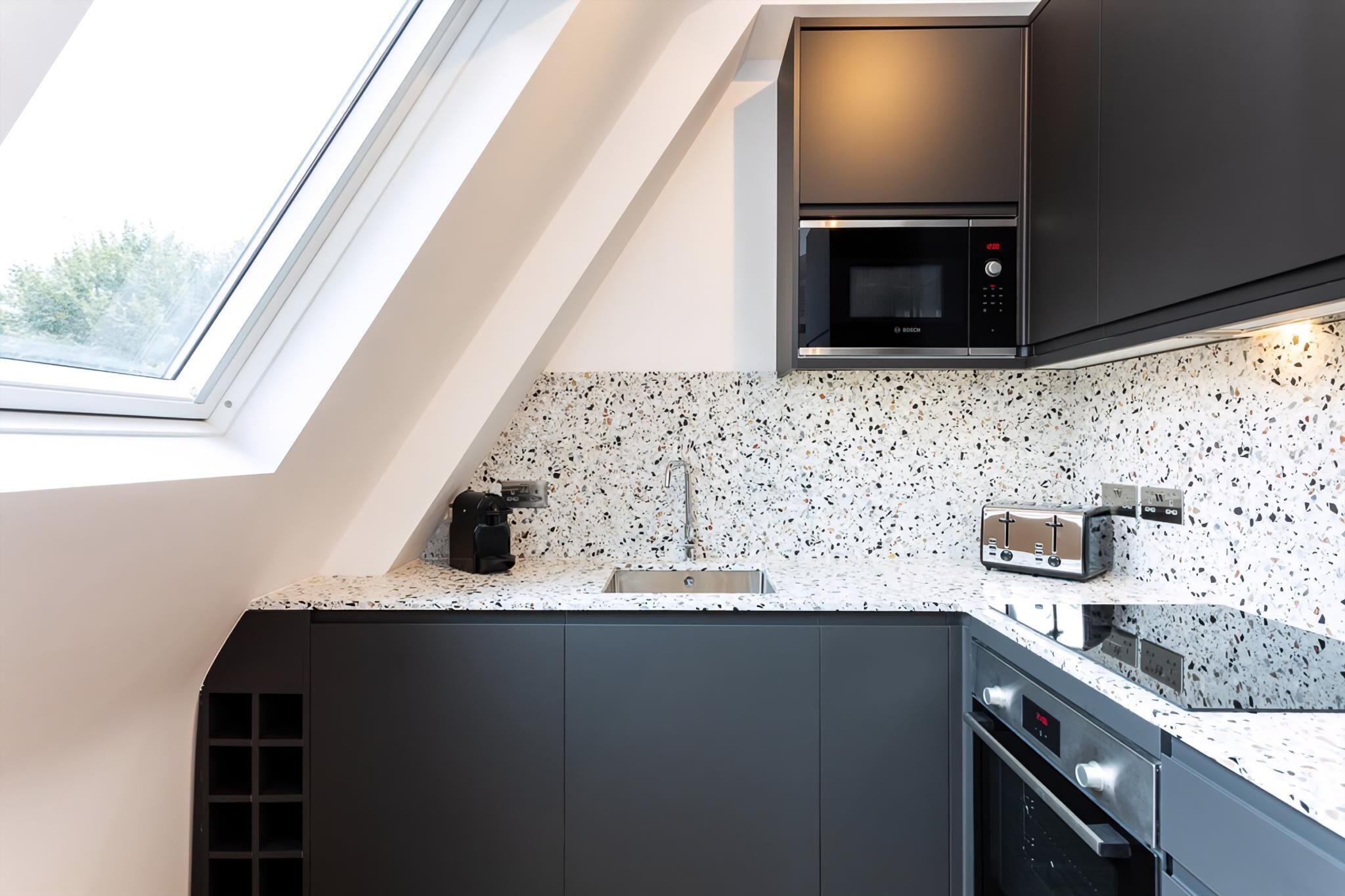 A modern kitchen with a skylight, a built-in microwave, a toaster, and a coffee maker.