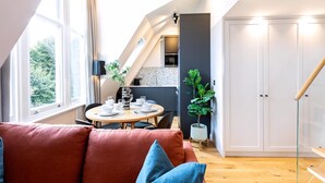 A modern loft-style apartment with a dining area, a kitchen, and a large window. - Coleherne Road Residence X (London)