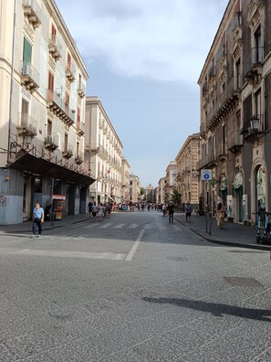 A street lined with historic buildings, a pedestrian crossing, and a street vendor. - Centro Città My House (Catania)