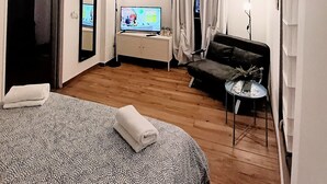 Une chambre d’hôtel moderne avec un grand lit, un canapé, une petite table et un téléviseur.