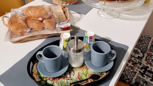 Une table de petit-déjeuner avec des viennoiseries, du pain et des tasses de café.