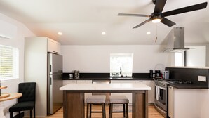 A modern kitchen with a central island, stainless steel appliances, and a ceiling fan. - Rainbow Canyon Retreat:  Hot Tub, Fire Pit, Games Room - Sleeps 16+ (Fallbrook)