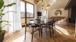 A modern living room with a dining area, large windows, and a view of the city. - Oro1 Florence Luxury Apartment by Mmega (Florence)