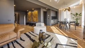 A modern living room with a sofa, a coffee table, and a dining area with a table and chairs. - Oro1 Florence Luxury Apartment by Mmega (Florence)