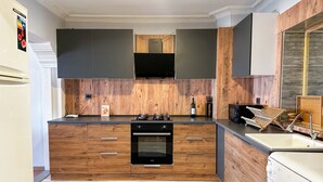A modern kitchen with wooden cabinetry, a built-in oven, and a stainless steel sink. - The Next Suites (Izmir)