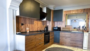 A modern kitchen with wooden cabinetry, a built-in oven, microwave, and dishwasher. - The Next Suites (Izmir)