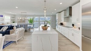 Een moderne keuken met witte kasten, een centraal eiland en roestvrijstalen apparatuur.