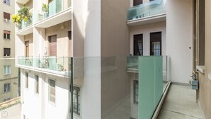 A multi-story residential building with balconies, a glass railing, and a visible water tap.