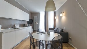 A modern kitchen with white cabinets, a microwave, and a dining area with a round table and chairs.