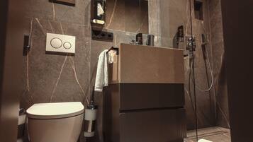 Un baño moderno con inodoro, lavamanos y zona de ducha.