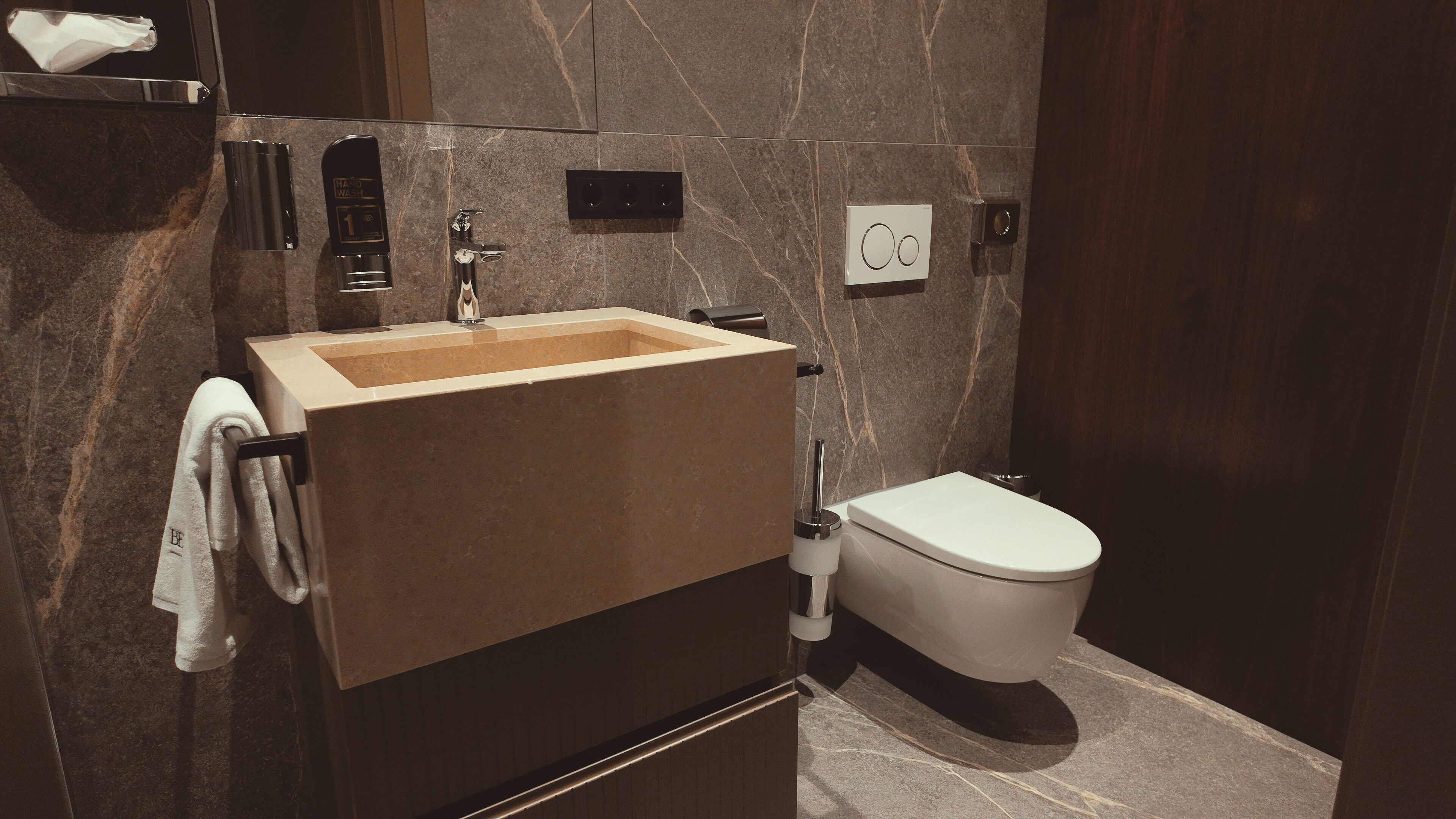 A modern bathroom with a beige sink, a toilet, and a towel rack.