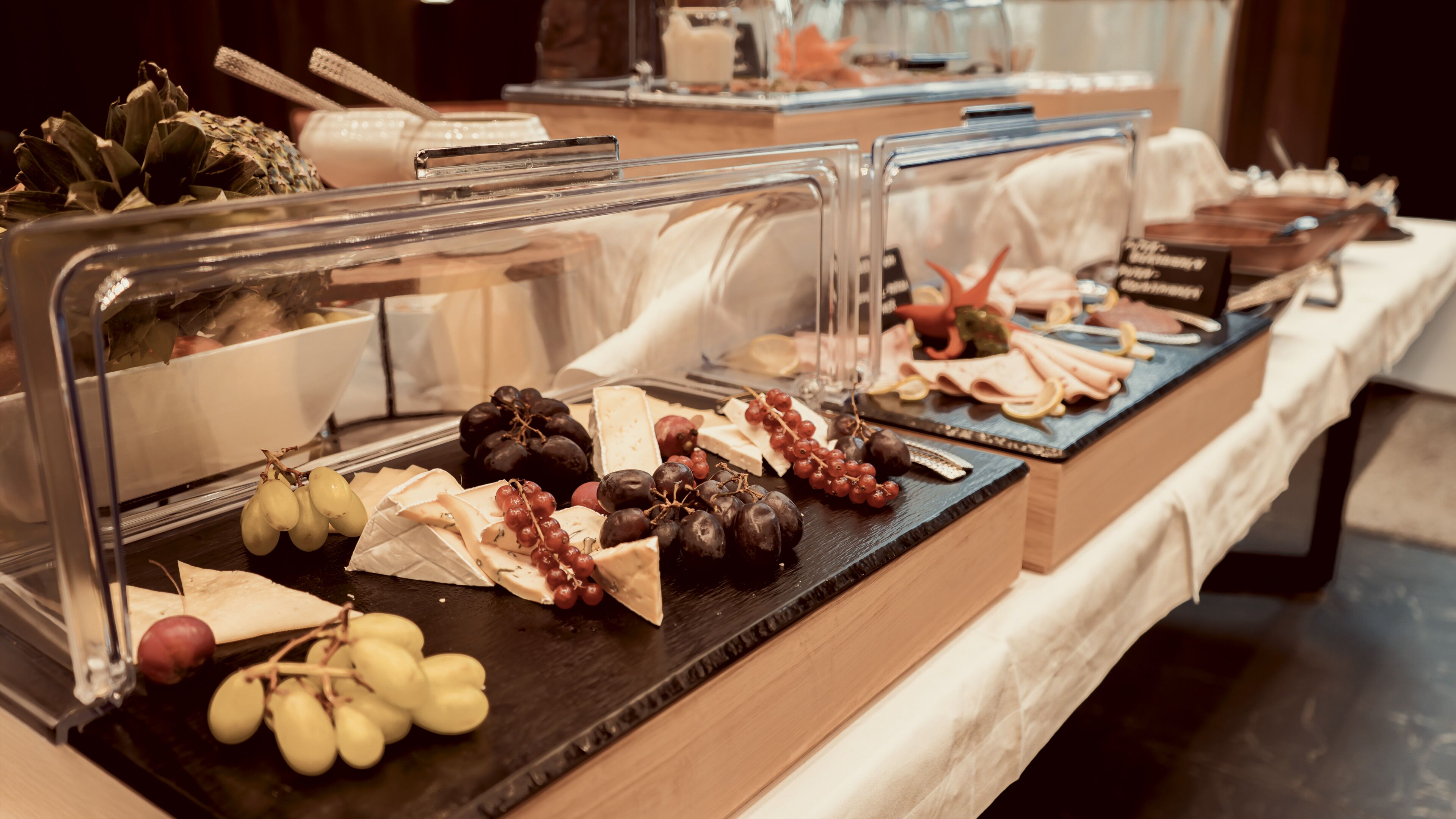 A buffet with various cheeses, fruits, and meats.