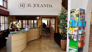 Un espace d’accueil doté d’un comptoir incurvé, d’une plante en pot et d’un panneau d’affichage où sont accrochées diverses annonces.