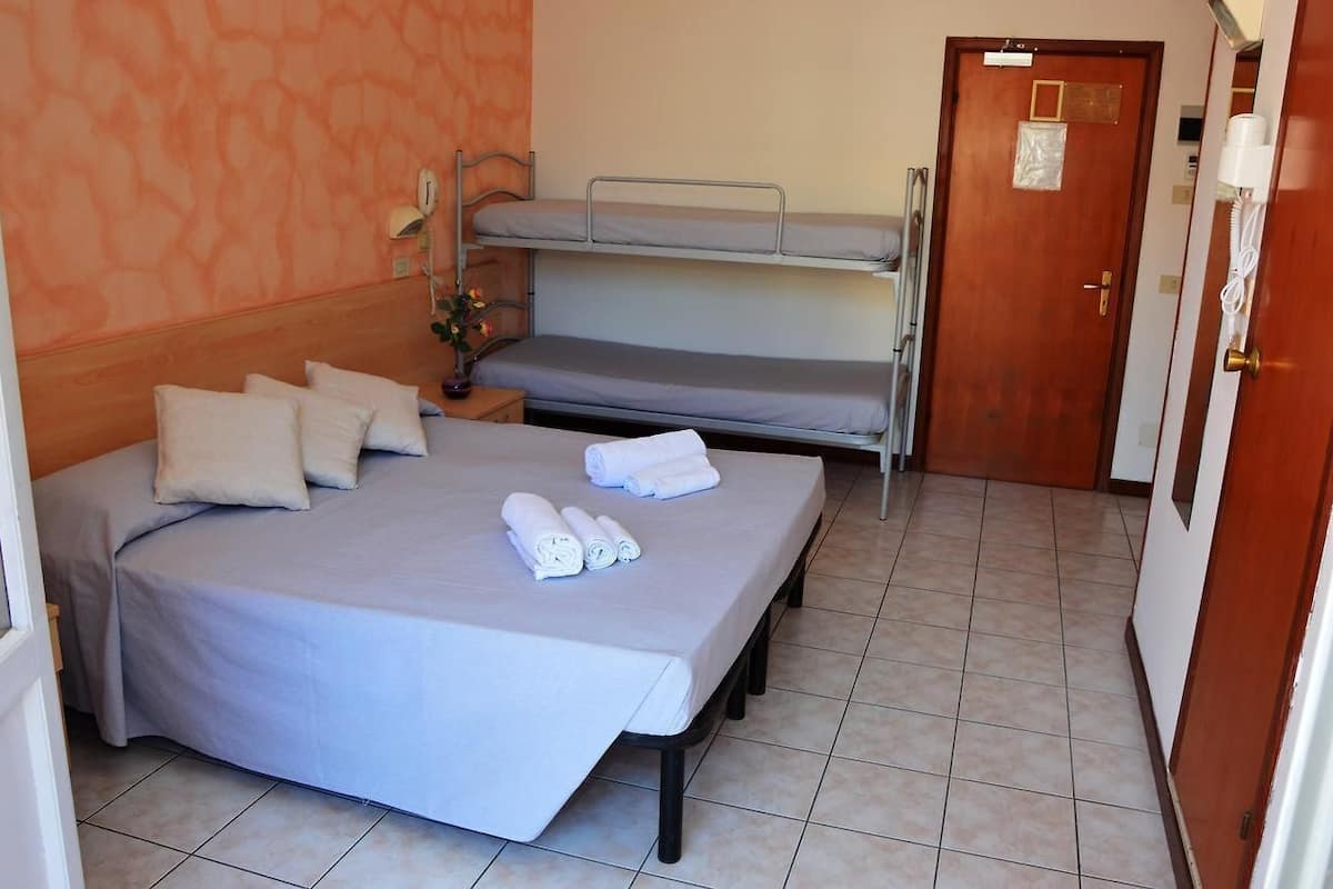 Une chambre avec un lit simple, un lit superposé et une porte.