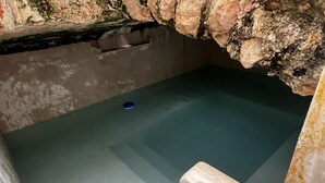 A stone-walled room with a small pool and a blue object on the floor. - Hotel Boutique Santa Elena (Mérida)