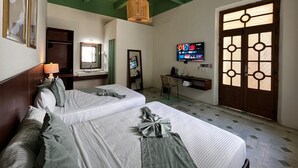 A hotel room with two beds, a desk, a TV, and a large window with a decorative door. - Hotel Boutique Santa Elena (Mérida)