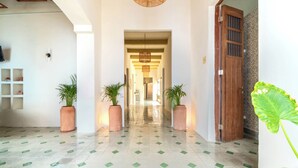 A hallway with a tiled floor, potted plants, and a wooden door. - Hotel Boutique Santa Elena (Mérida)