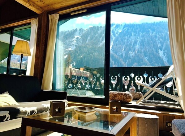 A cozy room with a large window, a sofa, a table with a bowl, and a chair. - Close to the slopes * View of Mont Blanc (Chamonix-Mont-Blanc)