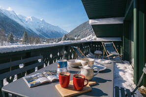 A table with a magazine, two red cups, a kettle, and bowls on a balcony with a snowy mountain view. - Close to the slopes * View of Mont Blanc (Chamonix-Mont-Blanc)