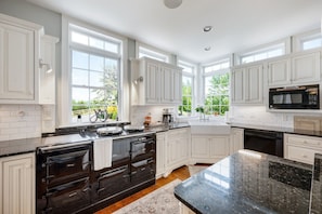 A kitchen with white cabinetry, a black stove, a microwave, and a large window. - Peony Hill Estate Retreat - The Summer House - Pool & Hot Tub (Lexington)