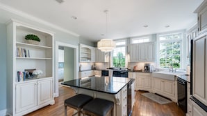 A spacious kitchen with white cabinetry, a central island with stools, and a large window providing natural light. - Peony Hill Estate Retreat - The Summer House - Pool & Hot Tub (Lexington)